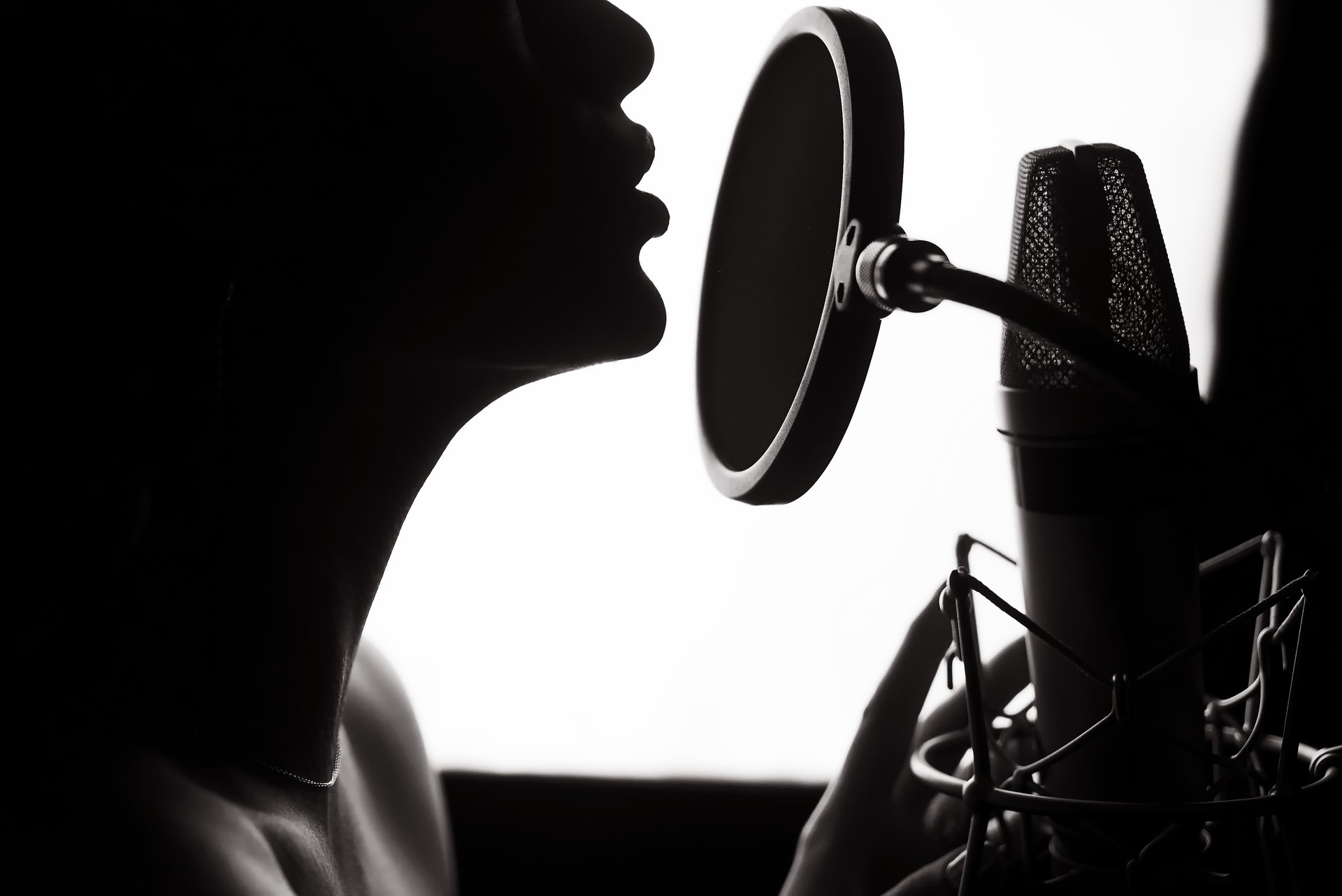 Silhouette of a woman singing a song in a recording studio.