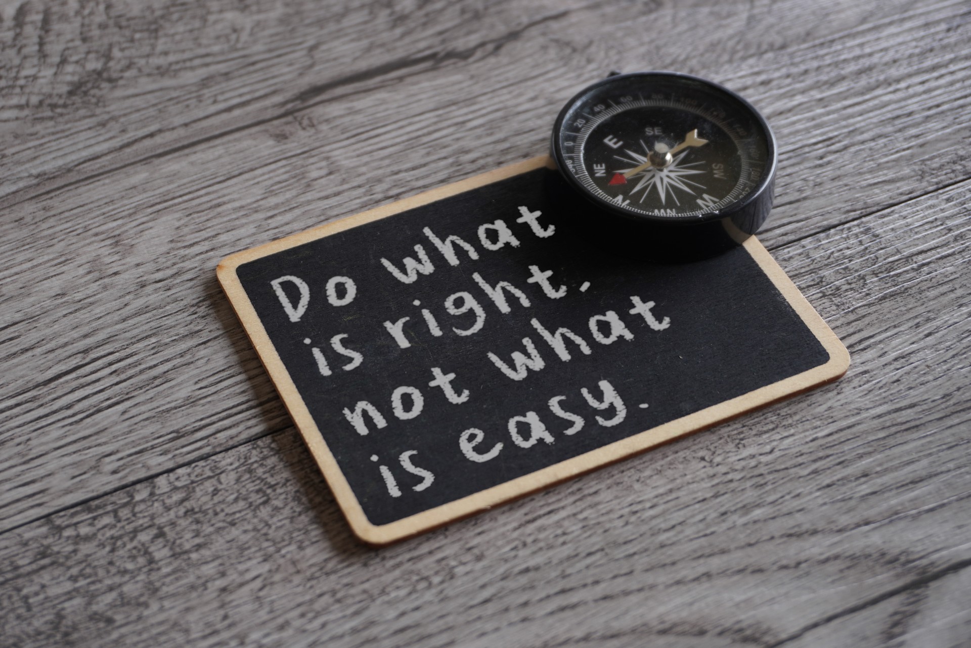 Closeup image of chalkboard with text DO WHAT IS RIGHT, NOT WHAT IS EASY and compass.